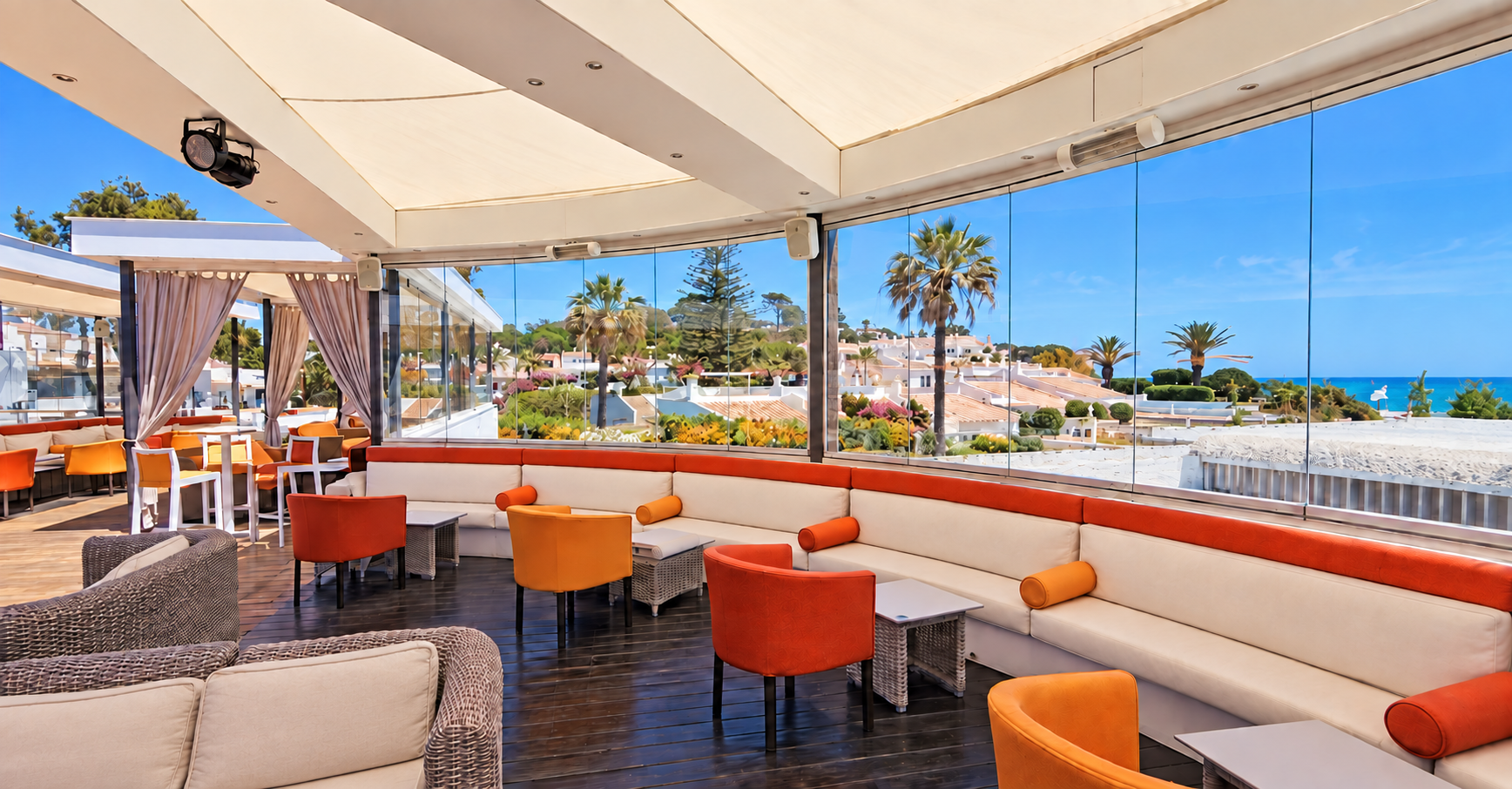 Esplanada coberta do Deck Bar com sofá curvo, cadeiras e vista para o mar